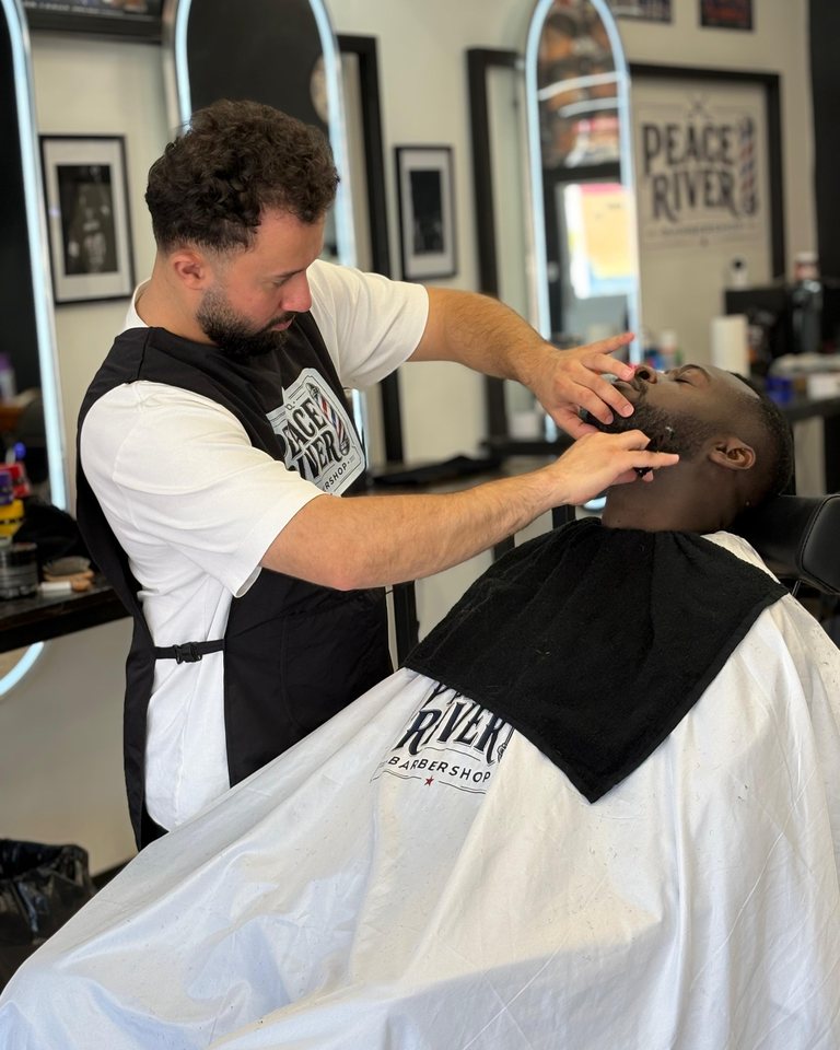 A barber carefully finishing a haircut in the shop