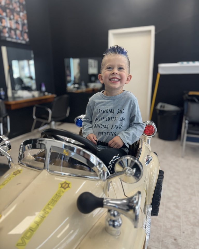 A young visitor smiling in the car barber chair
