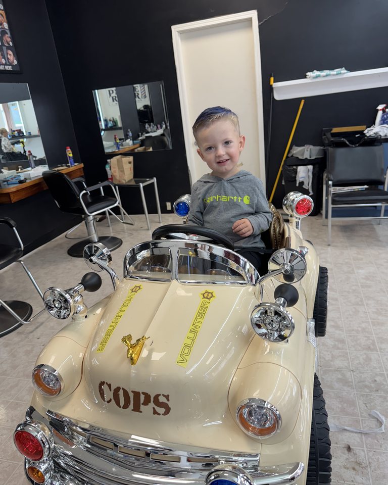 A child seated in the car barber chair