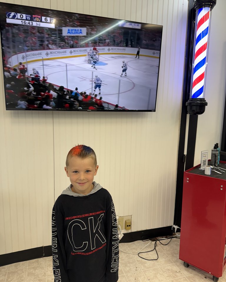A young visitor showing a finished haircut in the shop